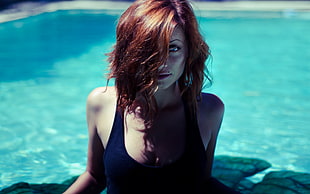 shallow focus photography of brown haired woman in black tank top at swimming pool